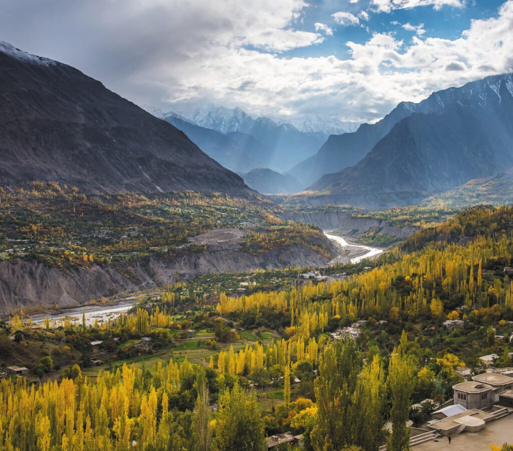 Panoramic view of Hunza Valley showcasing snow-capped peaks and lush green terraced fields