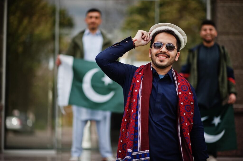 Group of Pakistani men wearing traditional salwar kameez and kurta, holding Pakistan flags